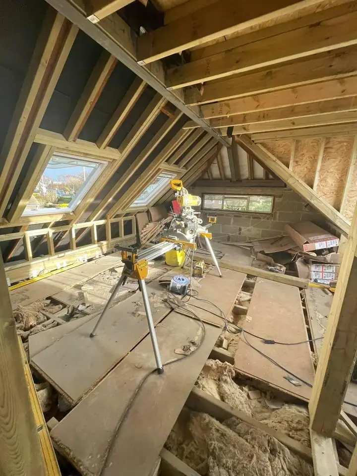 Inside a loft during the build: new rafters, a roof window, floor deck and blockwork gable wall